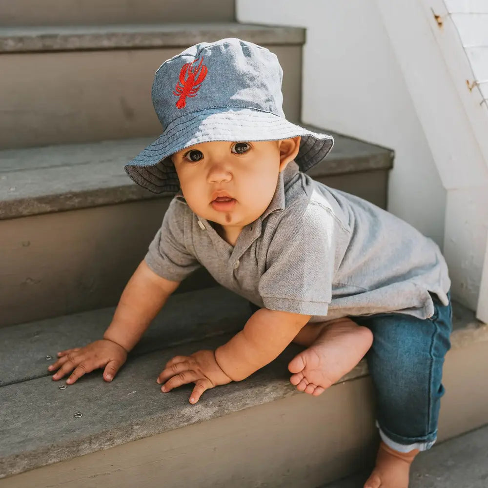Cute navy denim baby bucket hat with embroidered lobster motif, lightweight summer accessory.