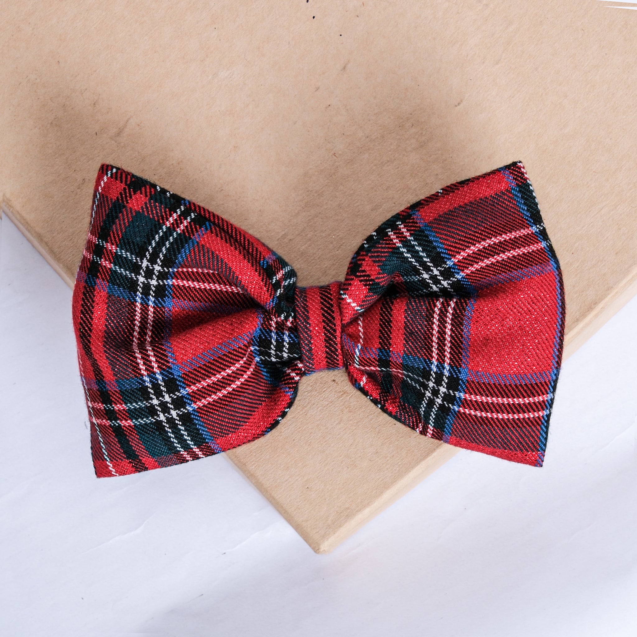Festive red plaid bow with holiday decor in the background.