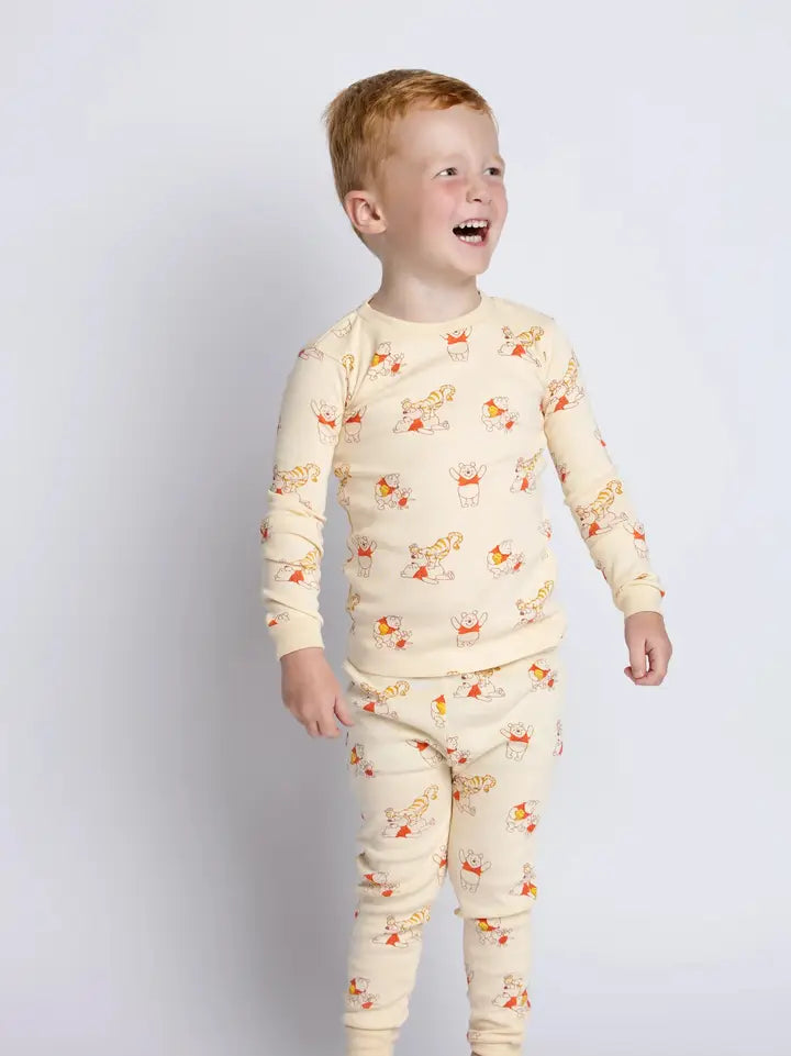 Disney Winnie the Pooh cotton pajama set featuring Pooh, Tigger, and Piglet on a soft cream background.