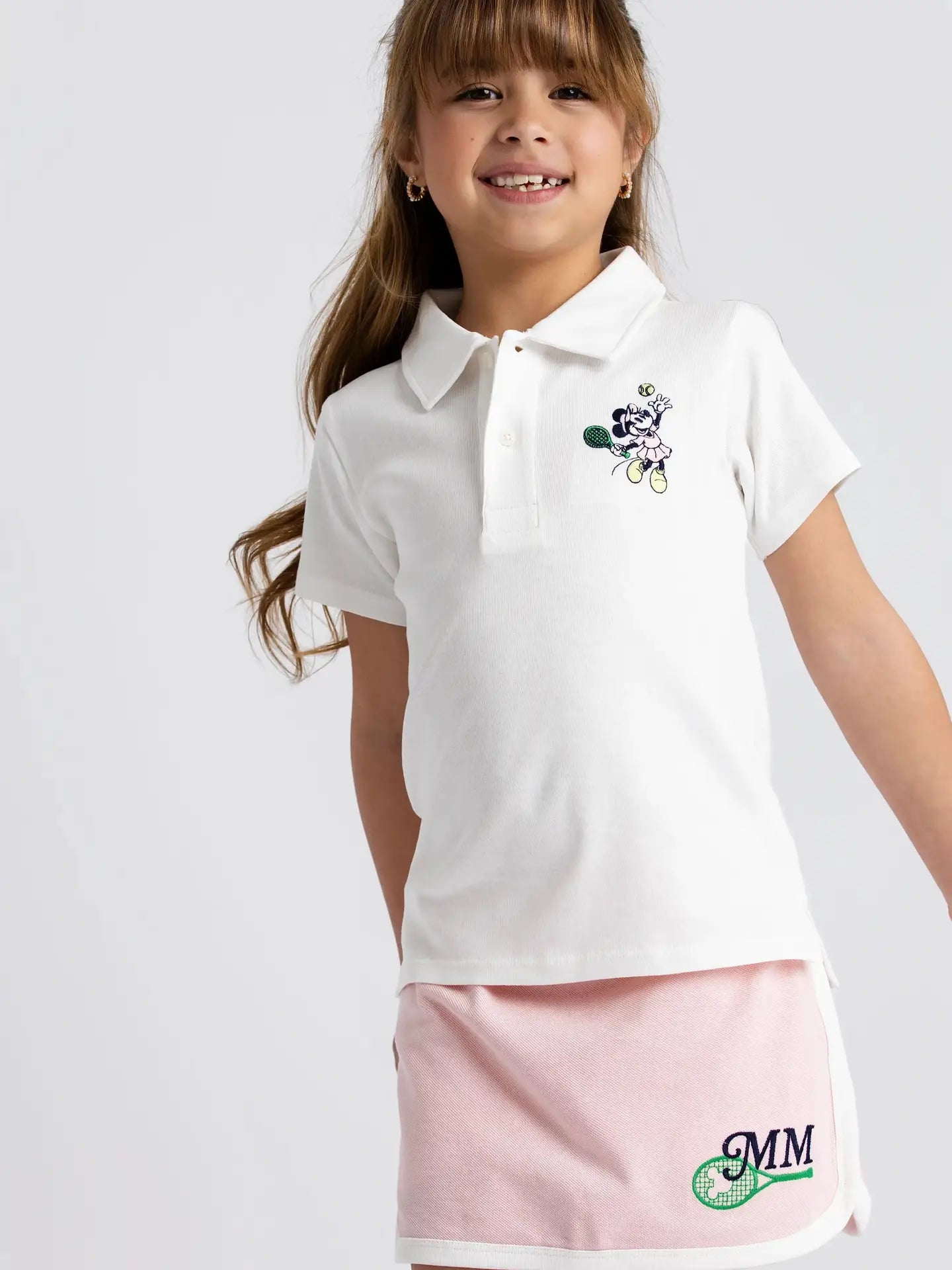 Toddler girl wearing Disney Minnie Mouse pink tennis skort with matching white polo shirt.