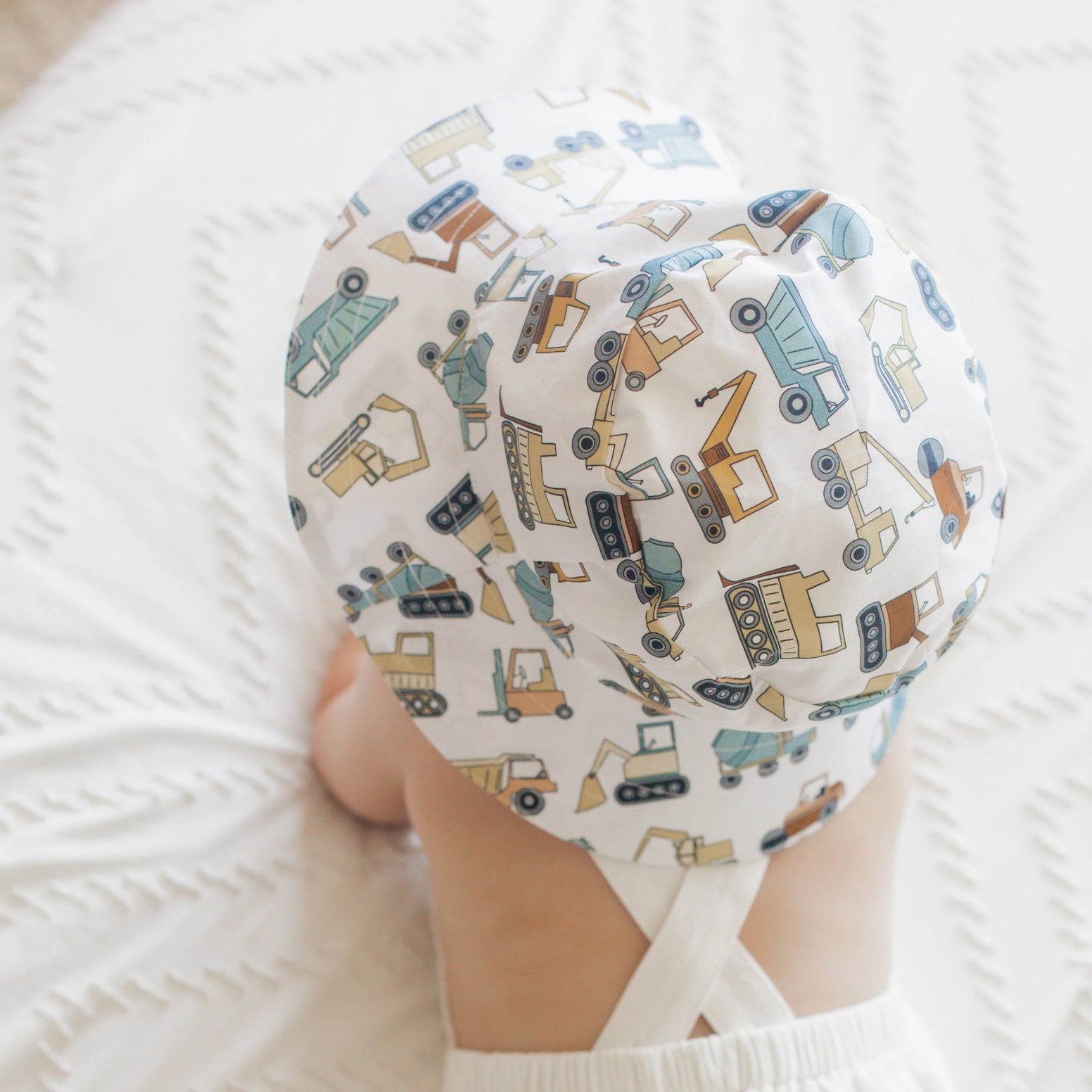 Baby wearing construction truck print sun hat