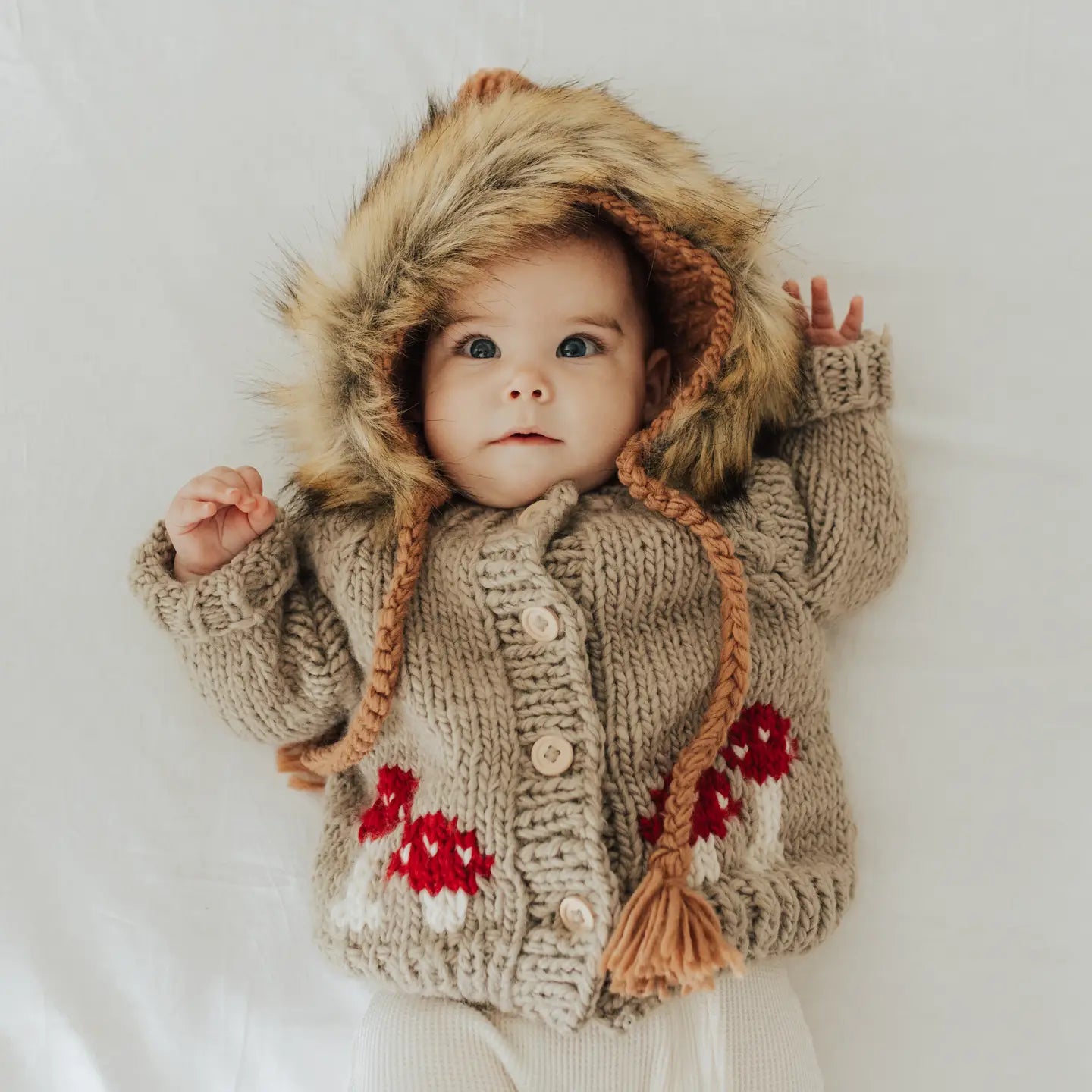 Chunky knit baby sweater in taupe featuring whimsical red toadstool mushrooms.