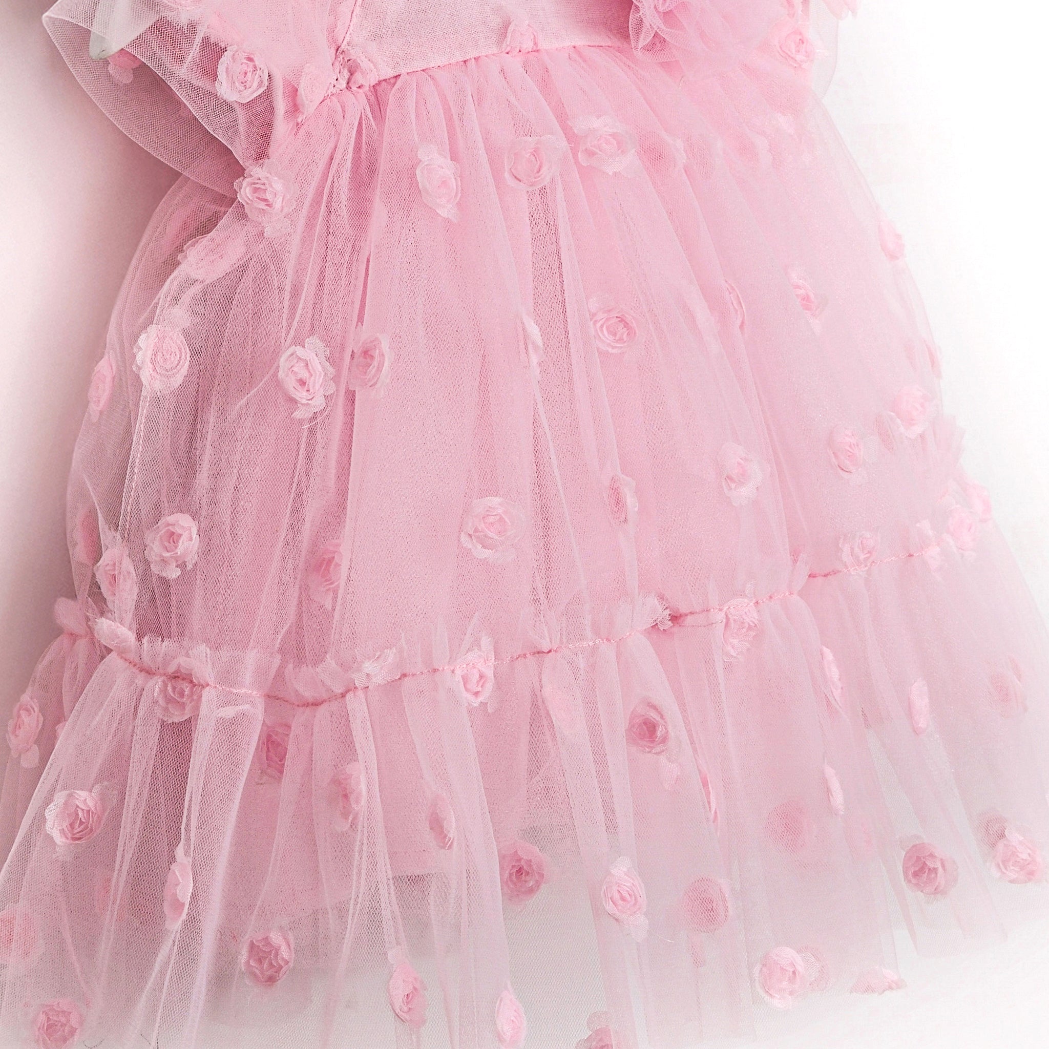 Delicate layered pink baby dress with tulle flowers and airy texture.