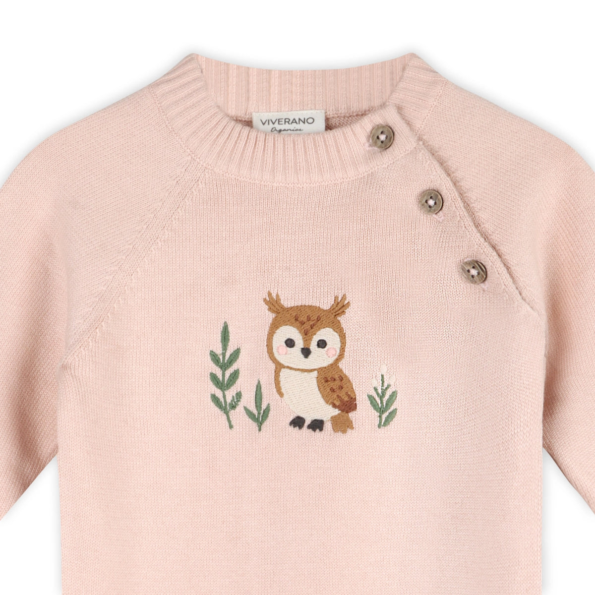 Close-up of pink knit baby jumpsuit featuring sweet owl embroidery and wooden-style buttons