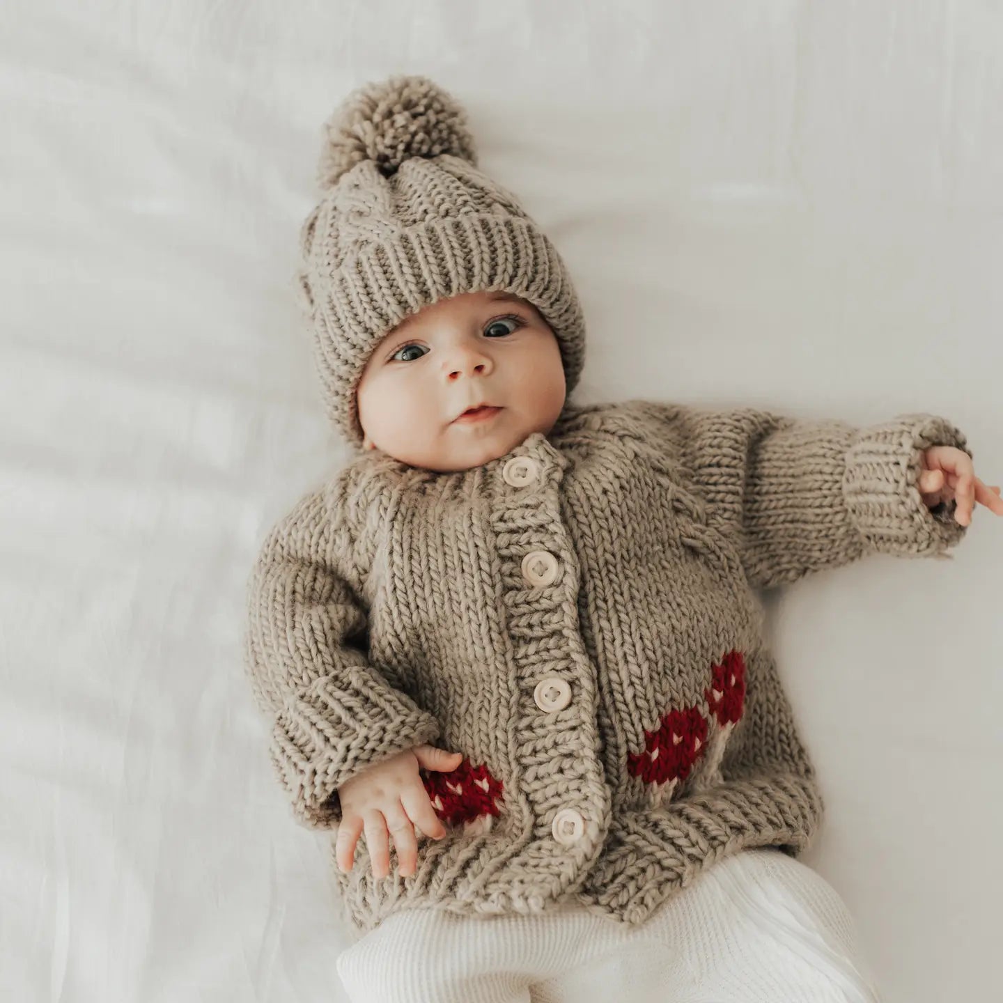 Cozy handmade infant cardigan with woodland mushroom design and natural button closure.