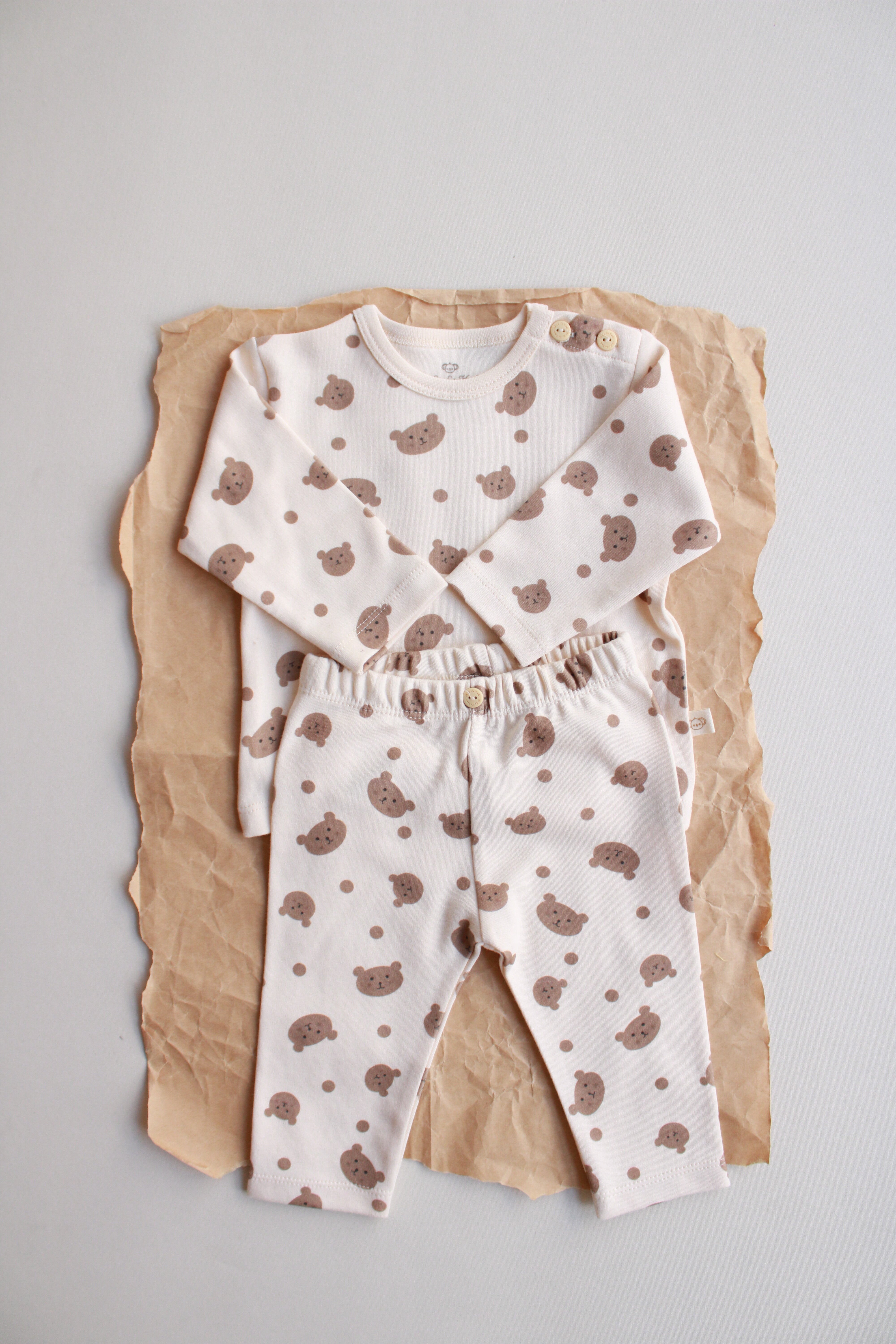 Neutral beige baby outfit with cute bear design and button-shoulder detail.