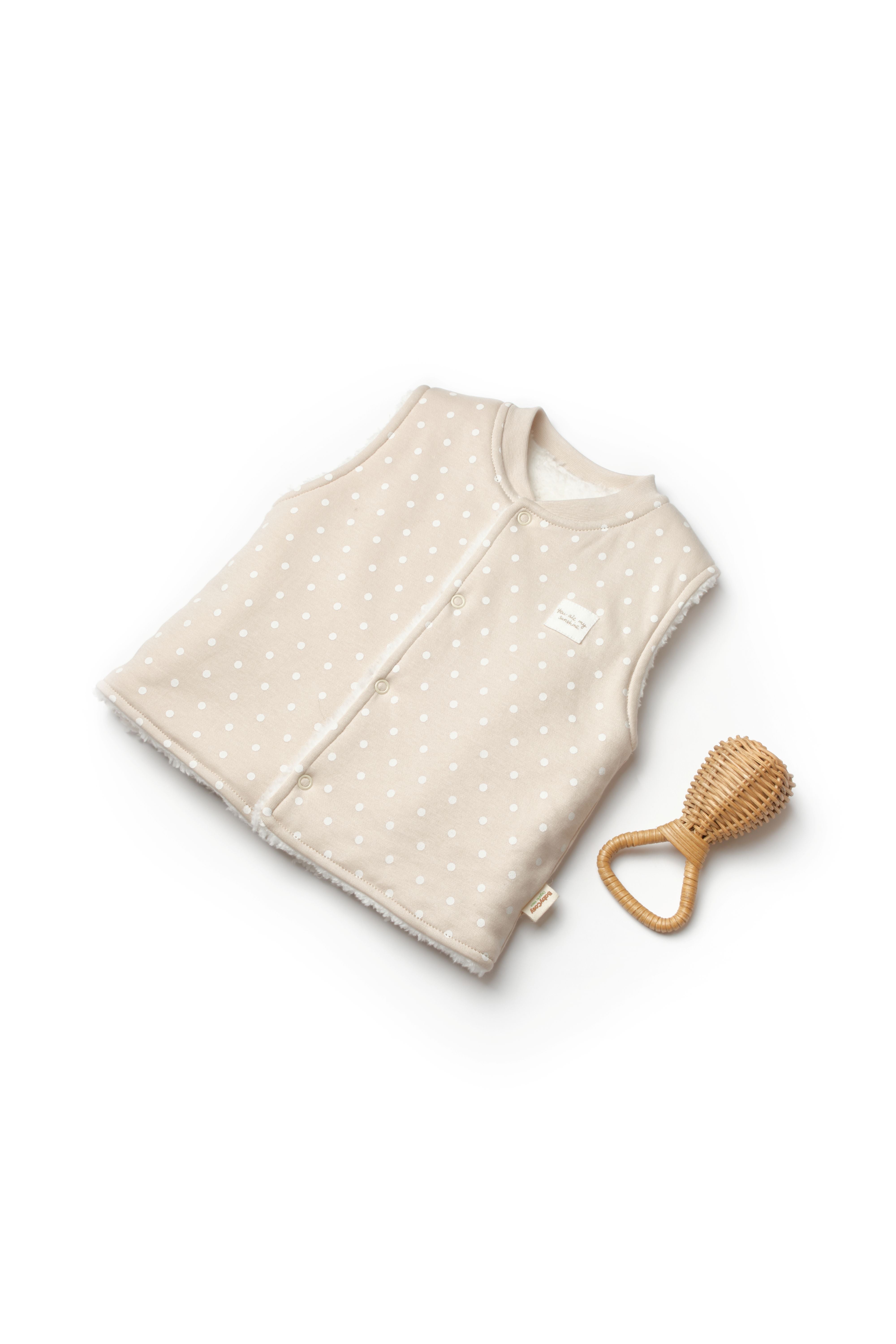 Beige organic baby vest with white polka dots and sherpa lining