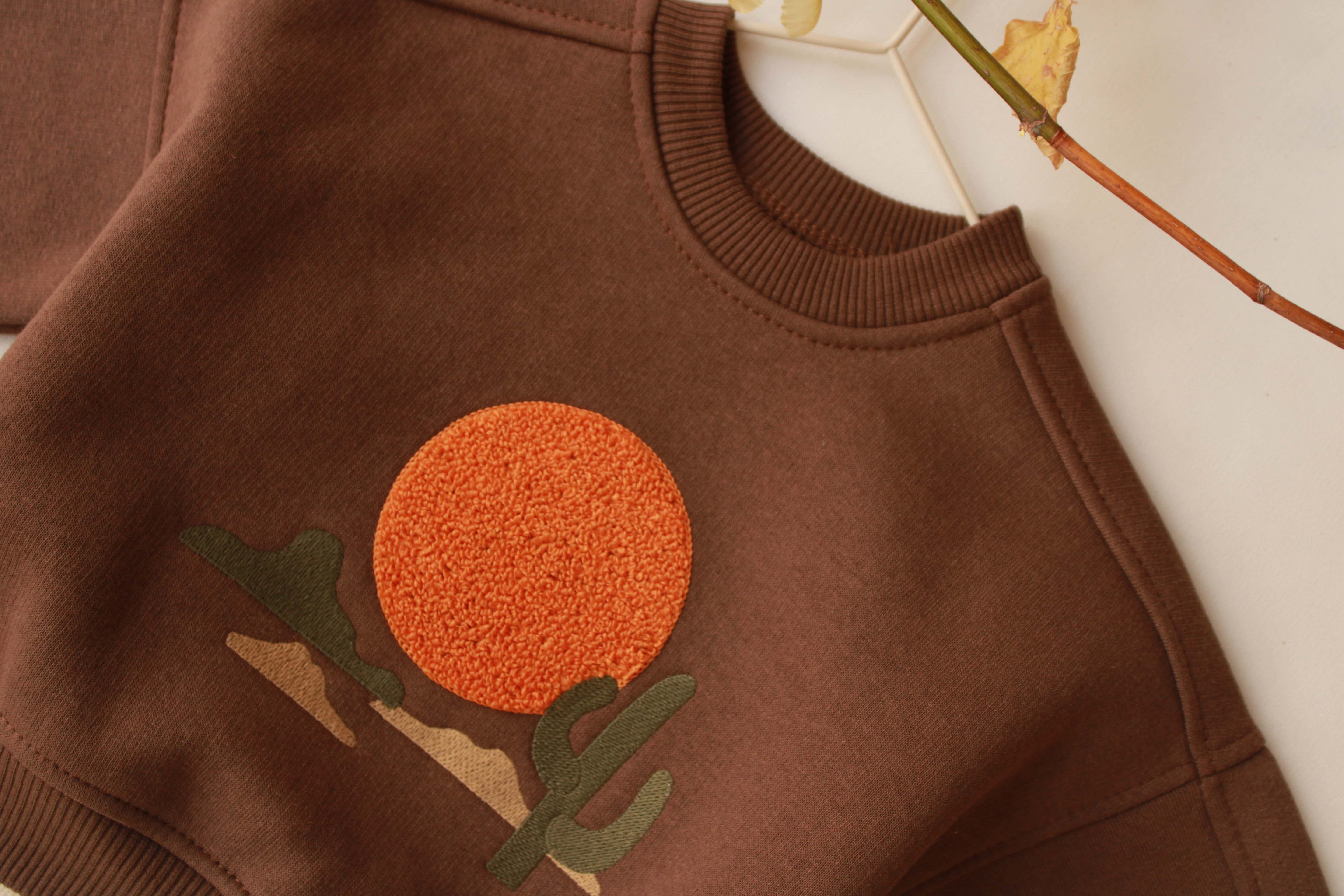 Neutral baby outfit with long-sleeve mountain graphic top and jogger pants.