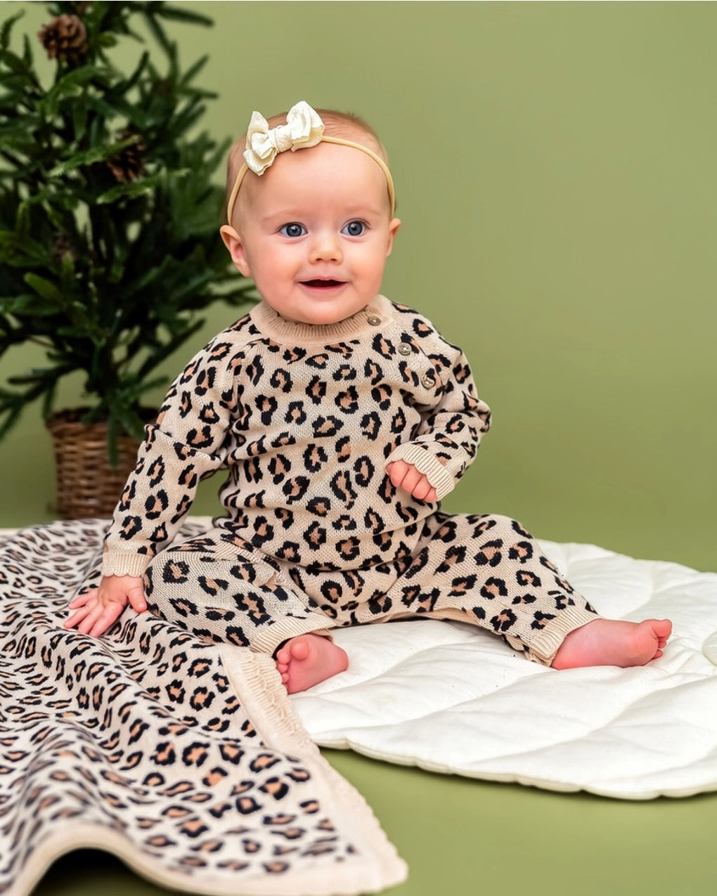 Baby wearing a neutral leopard print organic cotton knit jumpsuit