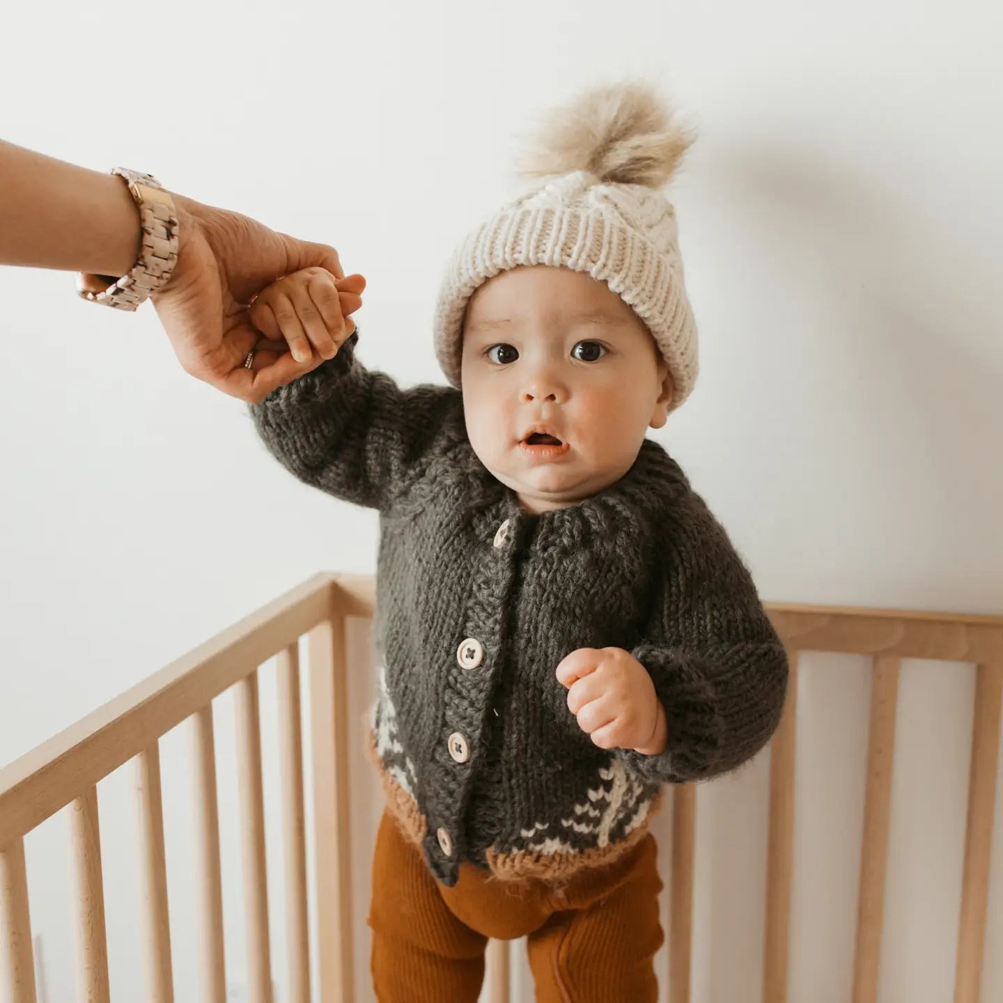 Cozy handmade baby cardigan featuring wooden buttons and brown cuffs with white knit trees