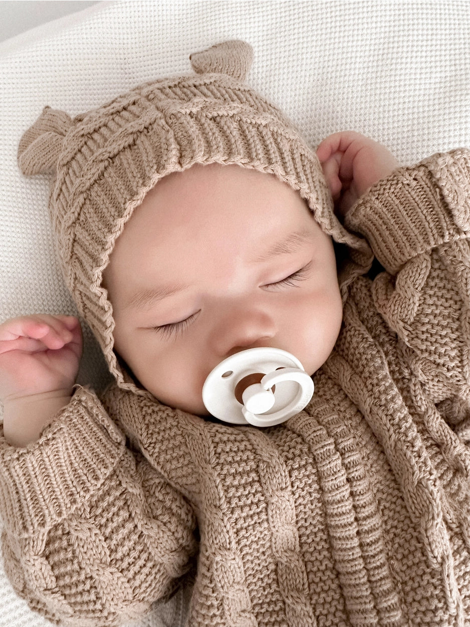 Neutral organic knit baby one-piece with zipper closure.