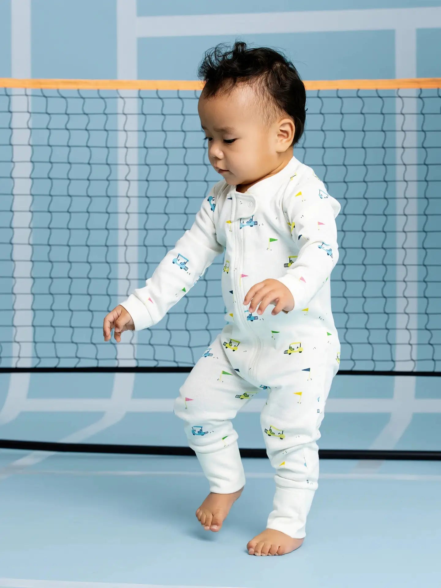 Baby golf print cotton zip sleeper featuring colorful golf carts and flags on a soft white background.