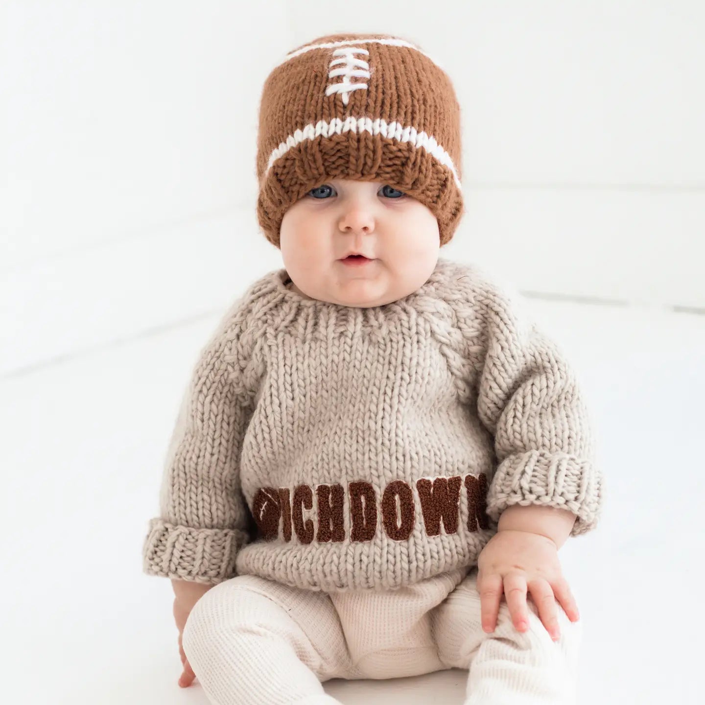 Baby wearing a knitted sweater and hat with 'Dichdown' text on a white background