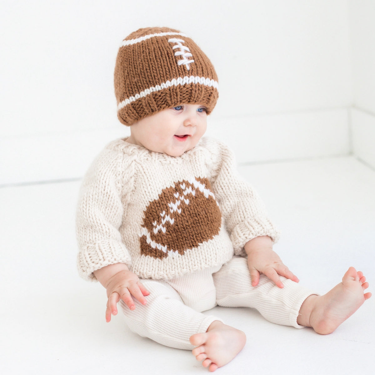 Cream knitted baby football sweater with brown football design and white laces