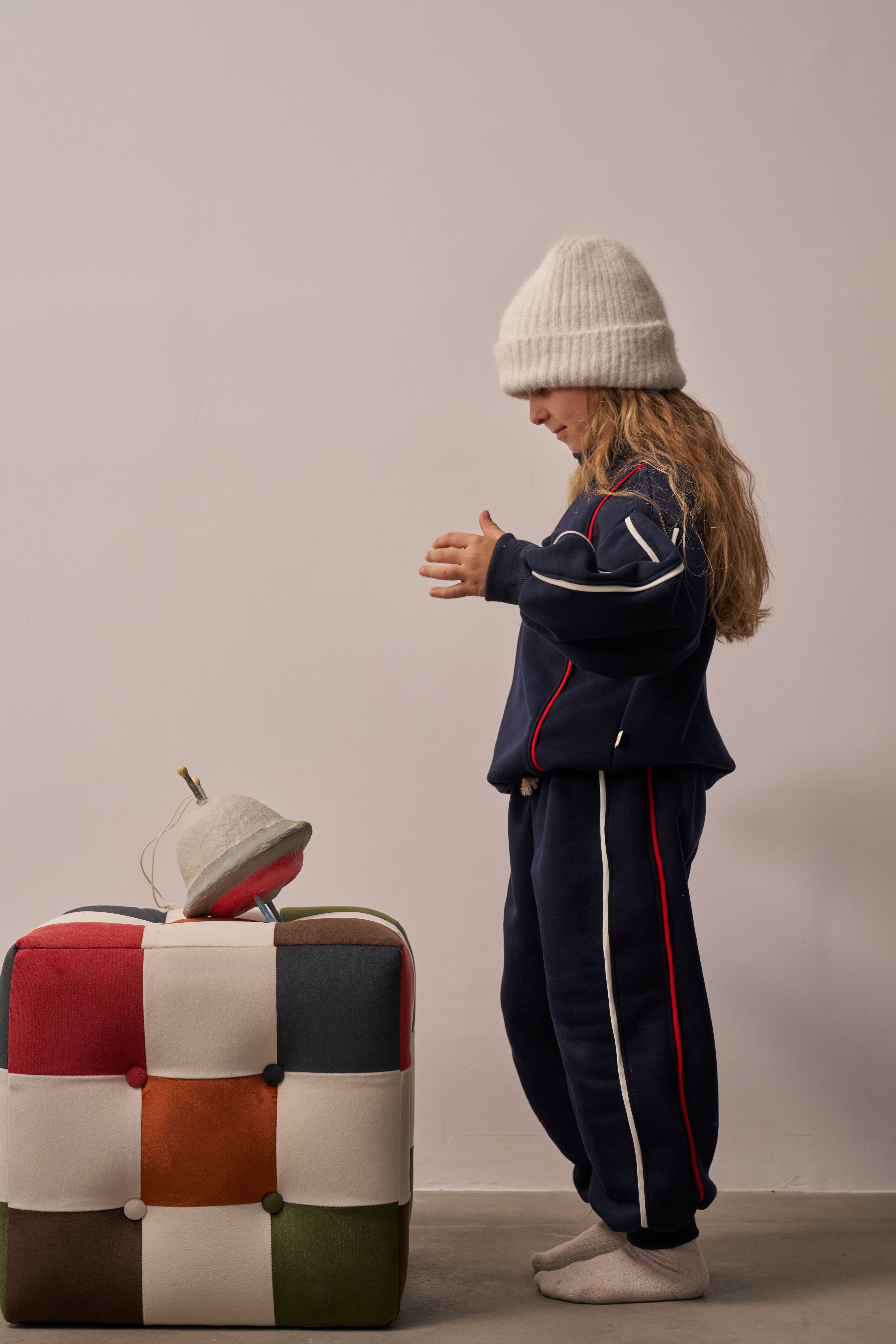Child wearing navy track suit with red and white piping details