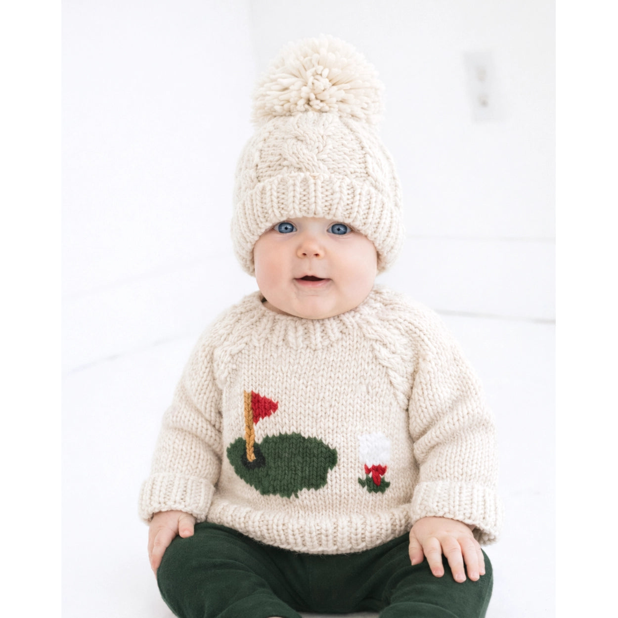 Cozy baby golf sweater with soft chunky knit and embroidered golf course details.