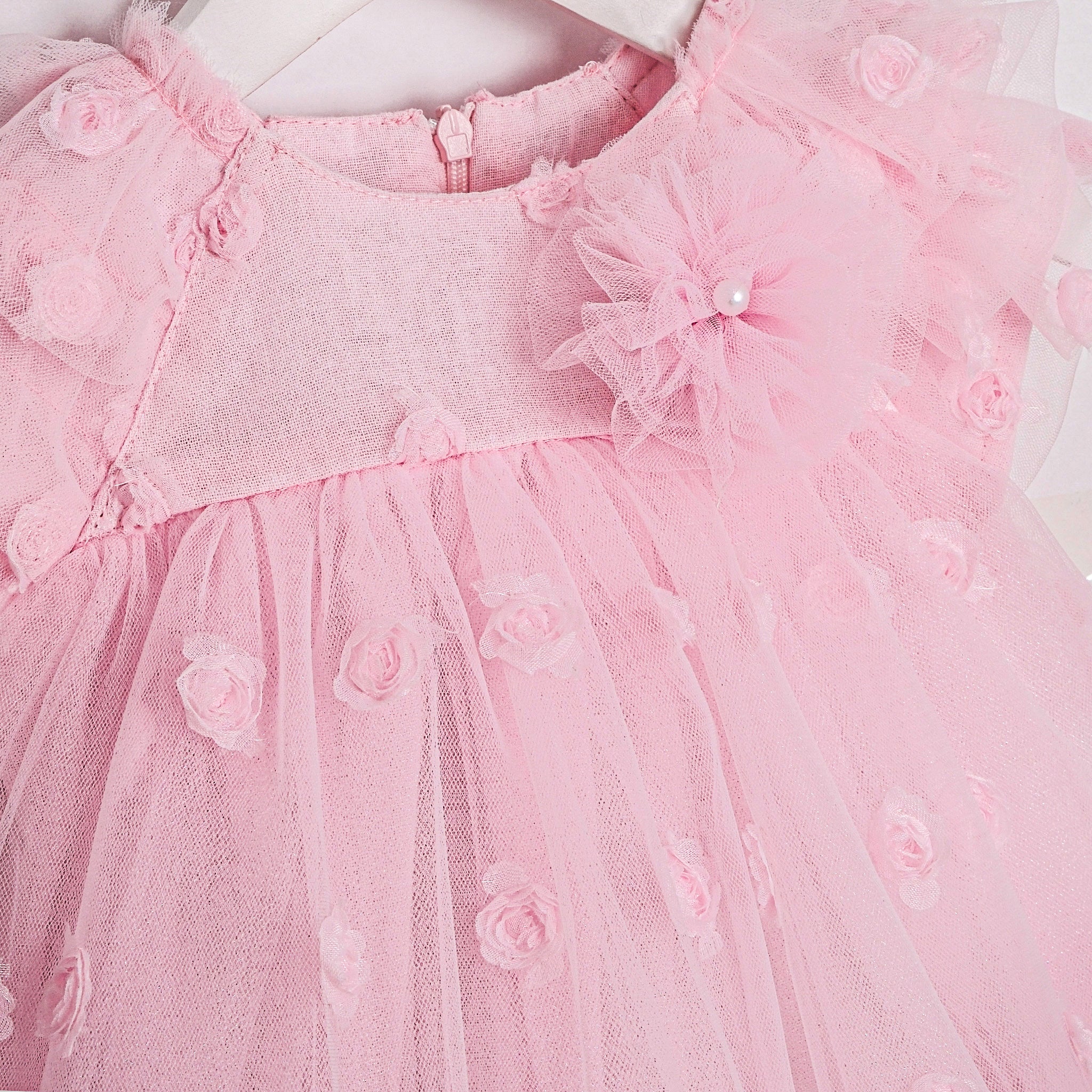 Soft pink tulle dress for baby girls with floral accents and ruffled sleeves.