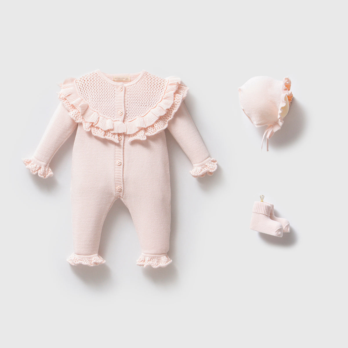 Blush knit baby romper with ruffle collar, bonnet, and socks