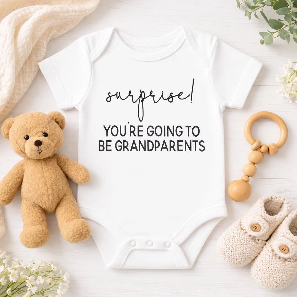 White baby onesie with “Surprise! You’re Going to Be Grandparents” pregnancy announcement lettering