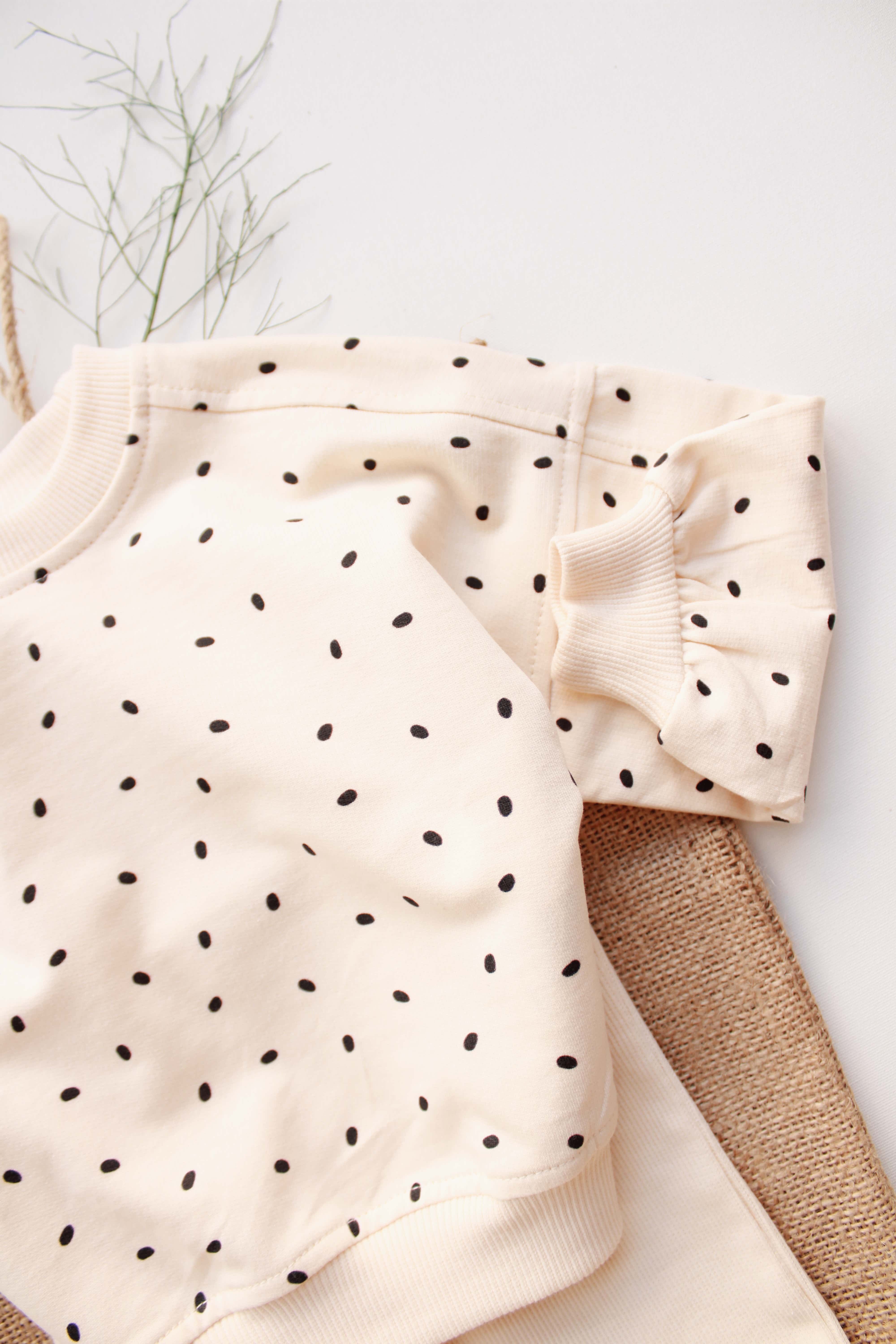 Soft beige baby clothes set with tiny black dot print and cuffed pants.