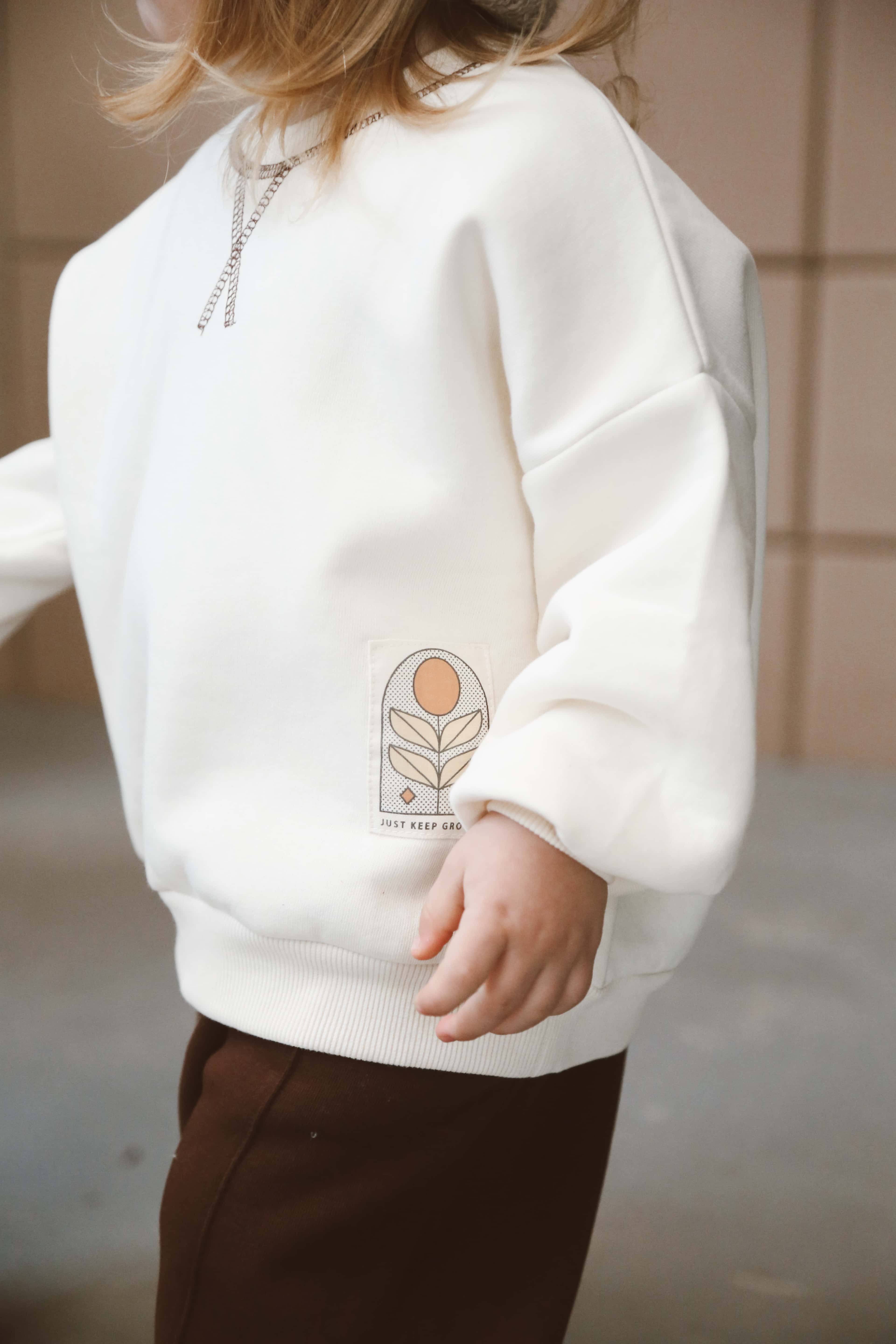 Minimalist toddler two-piece loungewear set in neutral cream and chocolate brown tones.