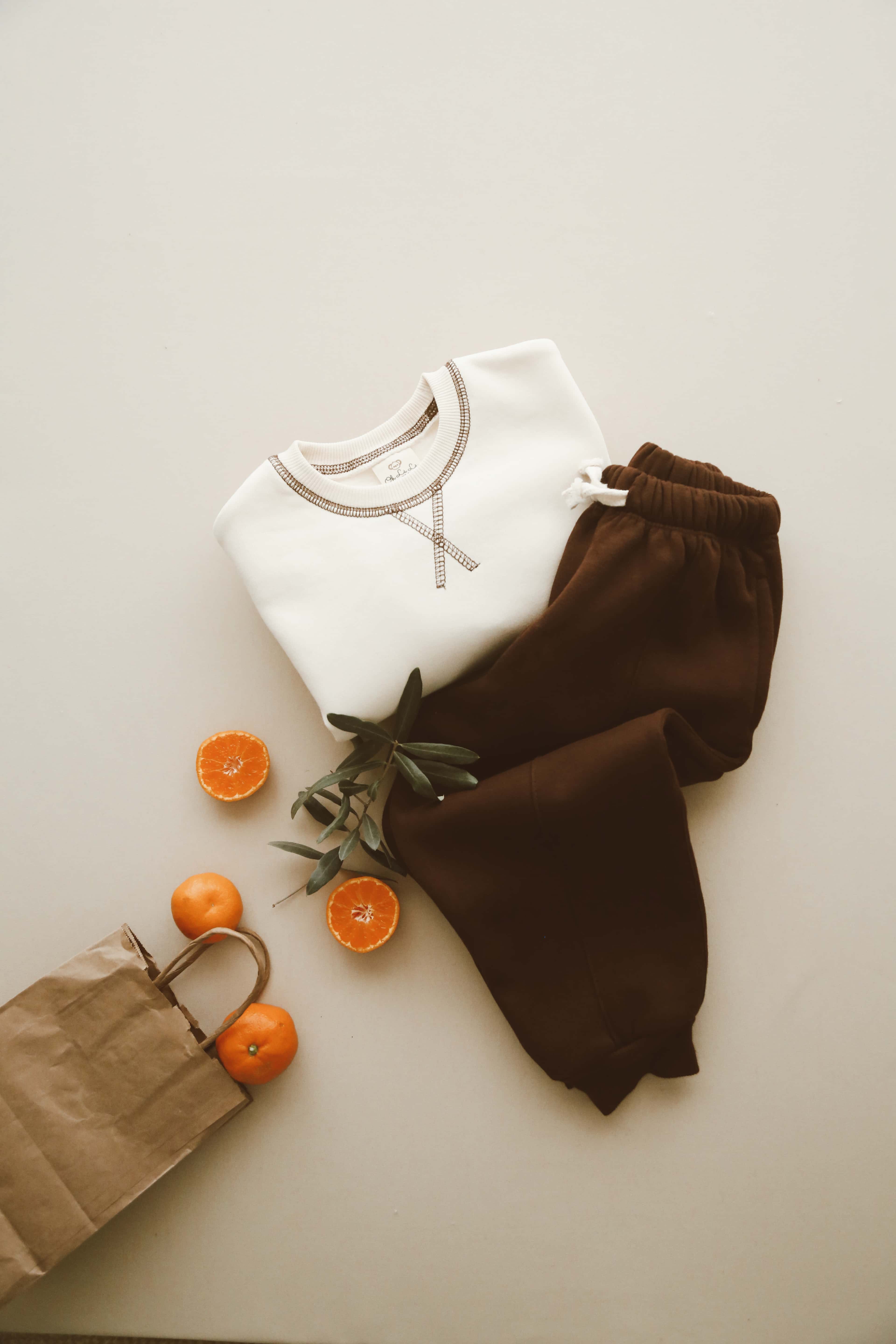 Neutral baby outfit with cream top and brown pants.