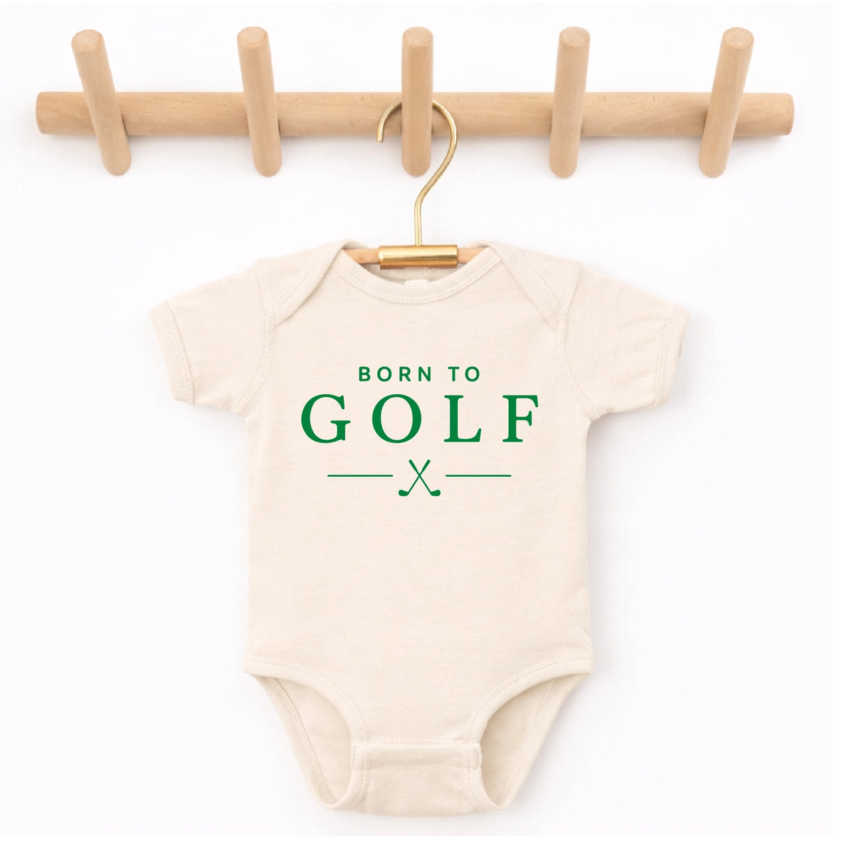 Cream Born to Golf baby onesie with green lettering and crossed golf clubs